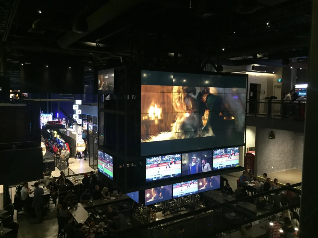 A view showing the large video wall and numerous other displays above the bar with the games area seen in the distance