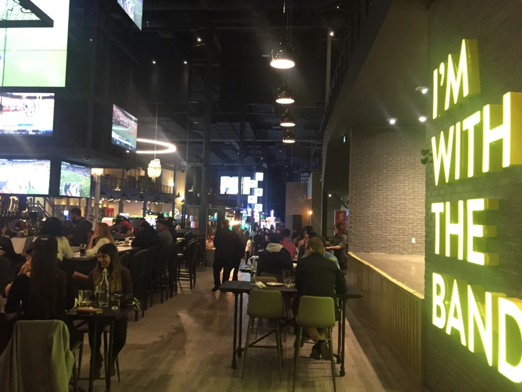 A view of the Rec Room bar area with an illuminated sign saying "I'm with the band" at the Rec Room South Edmonton Common